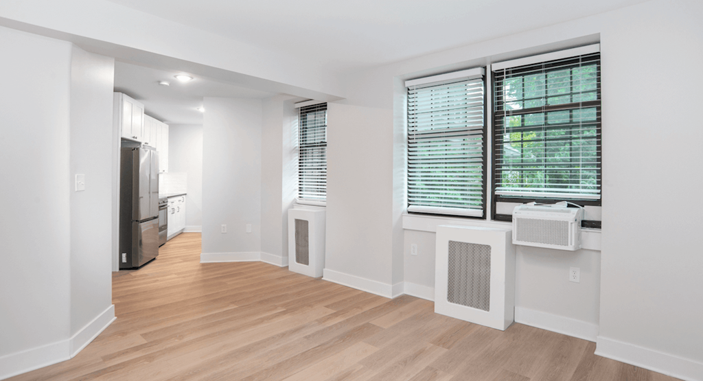 a living room and kitchen with white walls and wood floors