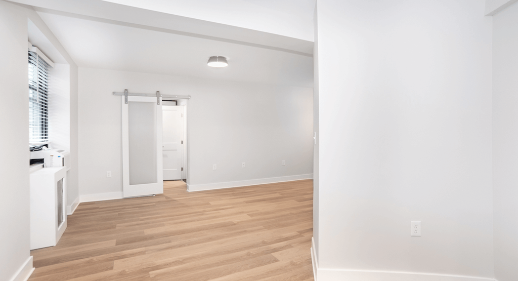 an empty living room with white walls and wood flooring