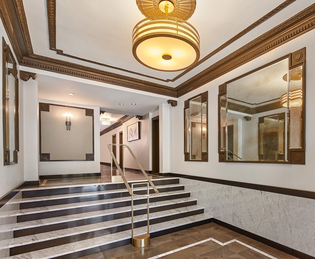 a lobby of a building with marble stairs and a gold chandelier