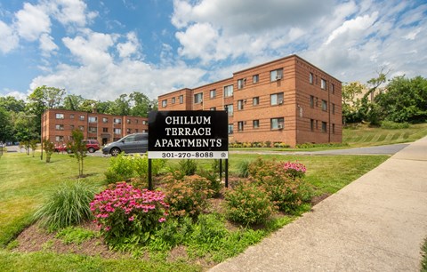 A sign for Chillum Terrace Apartments stands in front of a brick building.