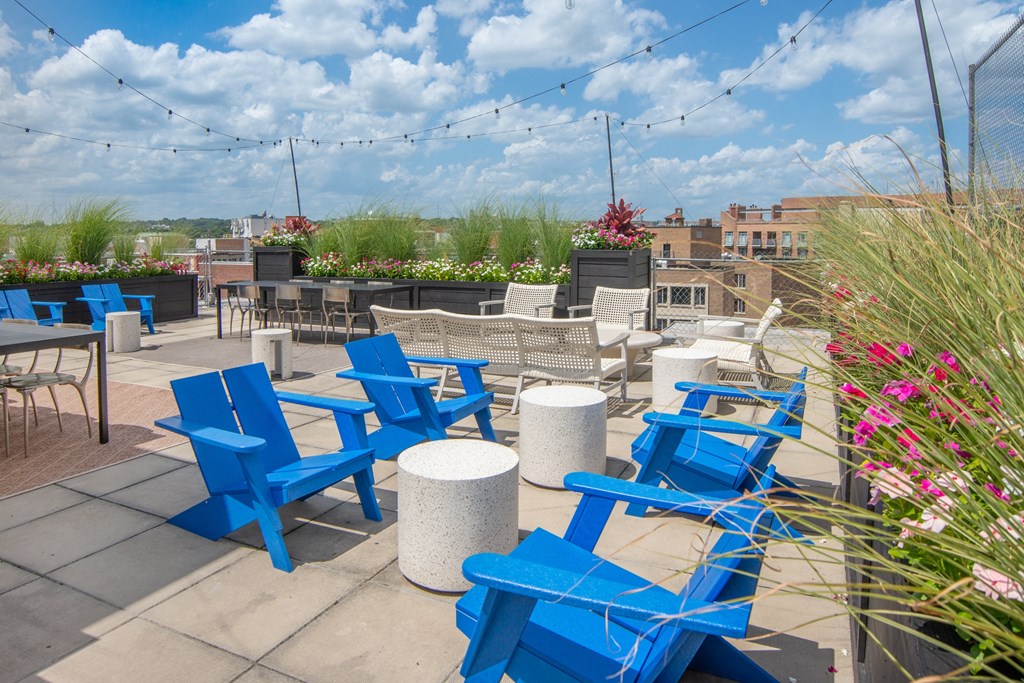 an outdoor patio with blue chairs and tables on a sunny day