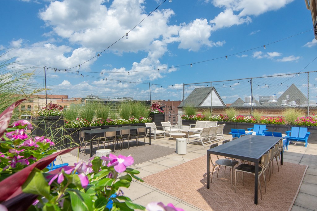 a rooftop patio with tables and chairs and flowers