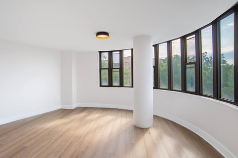 A white room with a wooden floor and a large window.