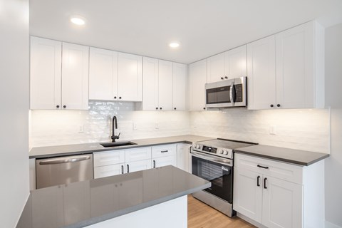 A modern kitchen with white cabinets and stainless steel appliances.