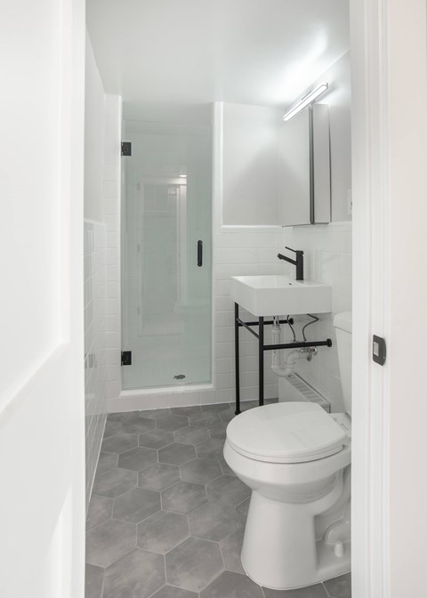 A white toilet in a bathroom with a white sink and a mirror.