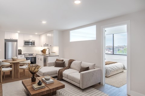 A modern living room with a kitchen in the background.