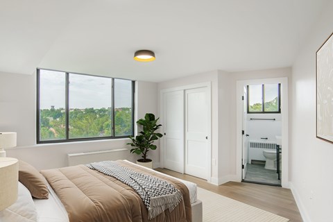 A bedroom with a large bed and a view of trees outside the window.