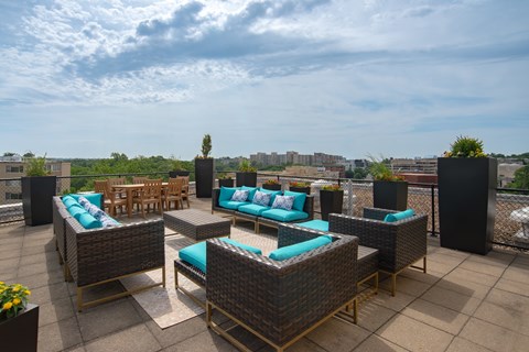 A patio with wicker furniture and blue cushions.