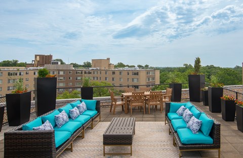 A patio with blue couches and a table surrounded by black speakers.