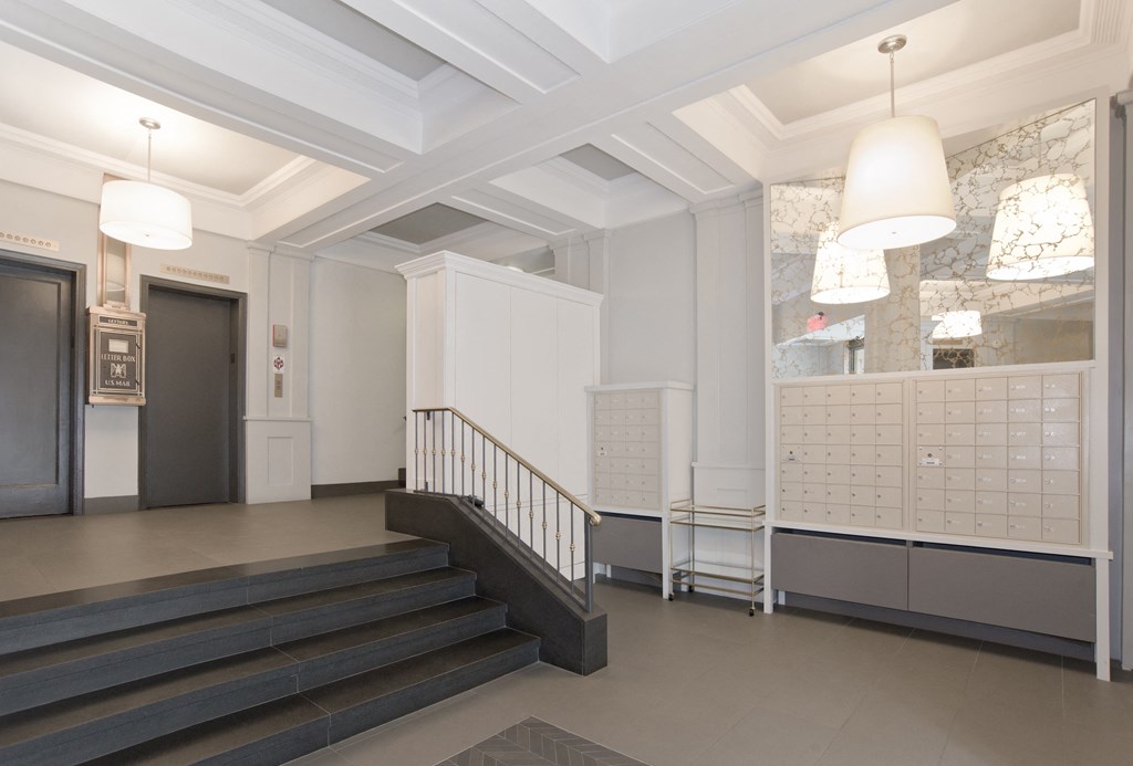the lobby of a building with stairs and a hallway with lockers and a staircase