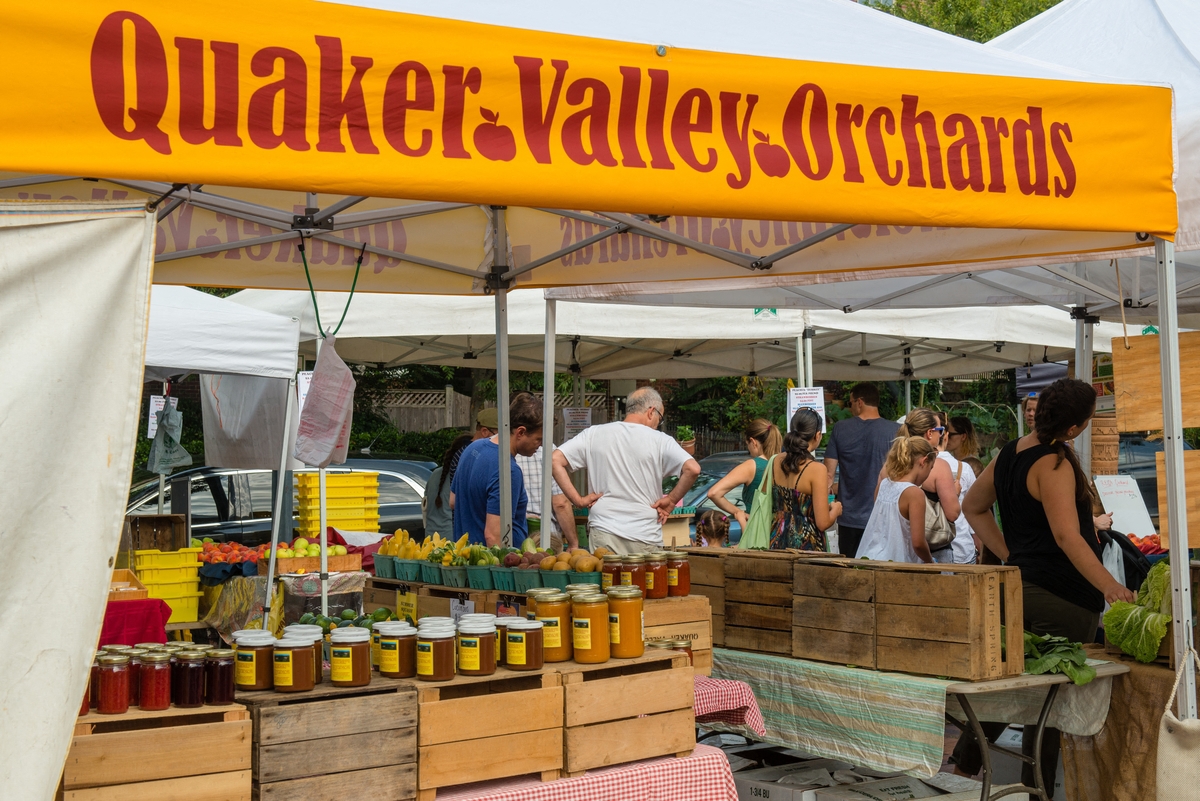 a stall at the farmers market with jars of fruit and vegetables