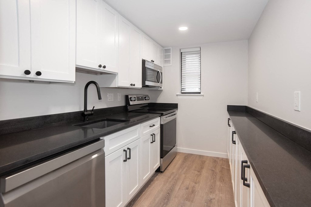 a kitchen with white cabinets and a black counter top