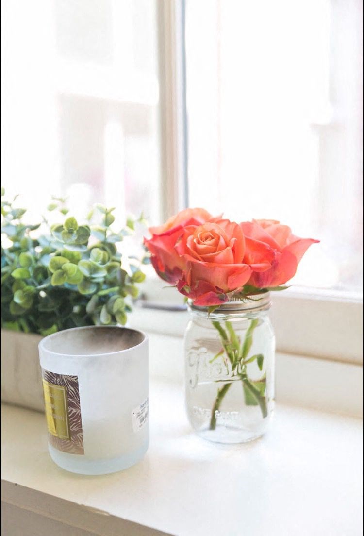 a vase with a rose on a window sill
