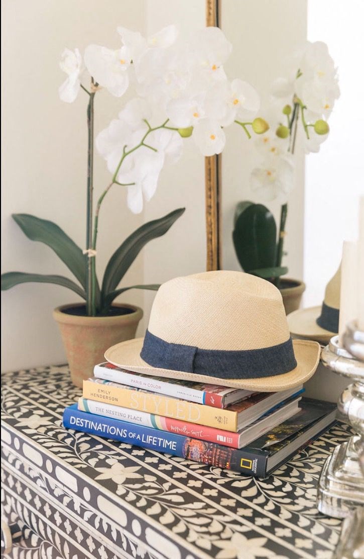a hat sitting on top of a stack of books on a table