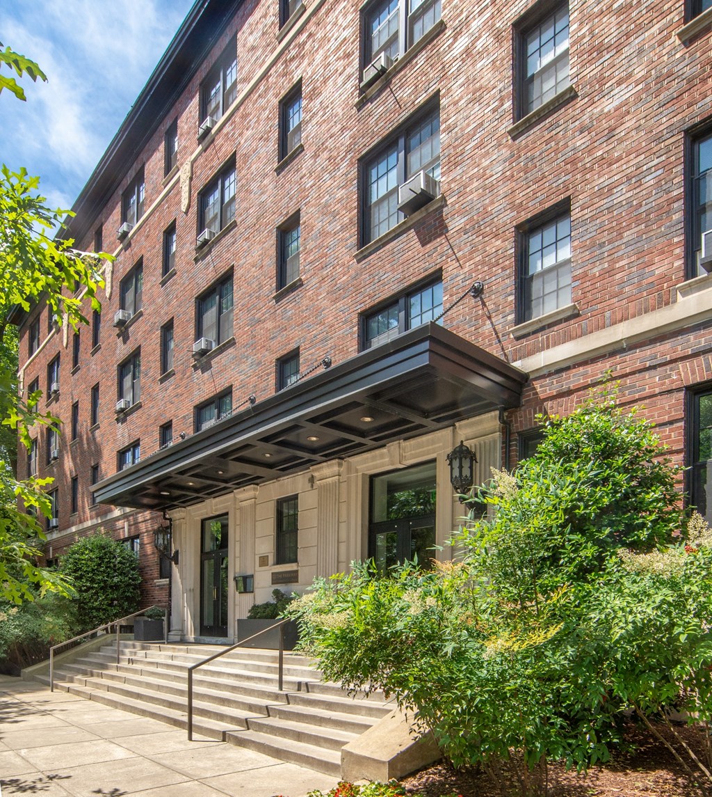 the front of a brick building with steps and plants