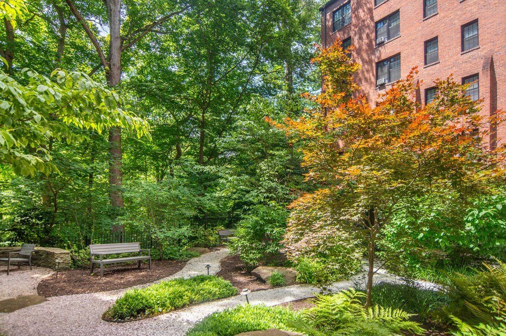 a park with benches and trees in front of a brick building