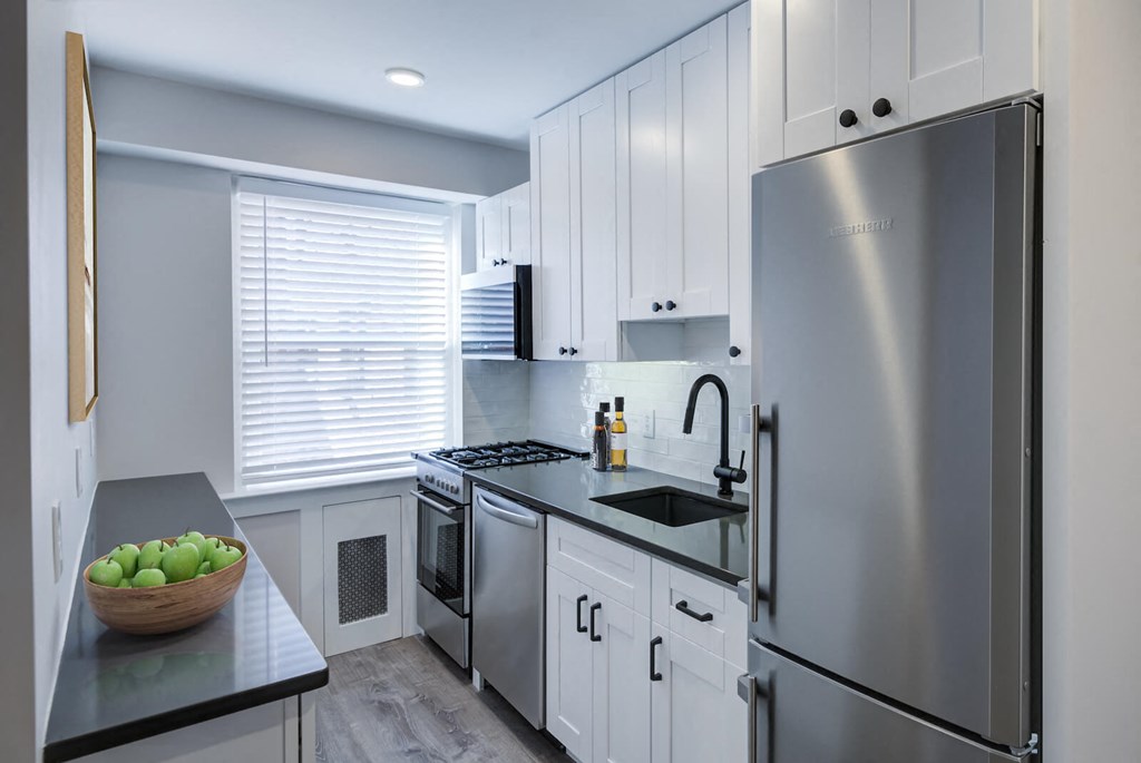 a kitchen with white cabinets and a stainless steel refrigerator