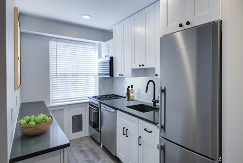 a kitchen with white cabinets and a stainless steel refrigerator