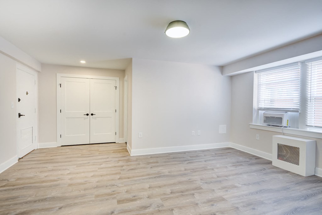 an empty living room with white walls and a white door and window