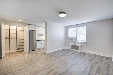 an empty living room with a refrigerator and a window
