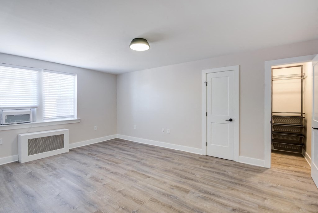 an empty living room with a white door and a window