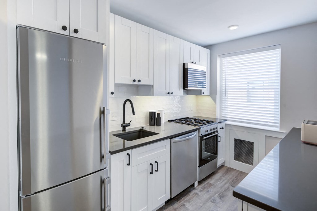 a white kitchen with stainless steel appliances and white cabinets