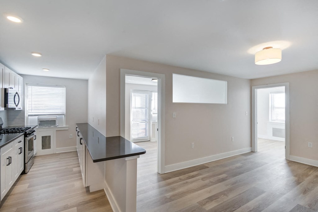 a renovated kitchen and living room with white walls and wood floors