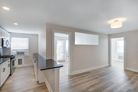 a renovated kitchen and living room with white walls and wood floors