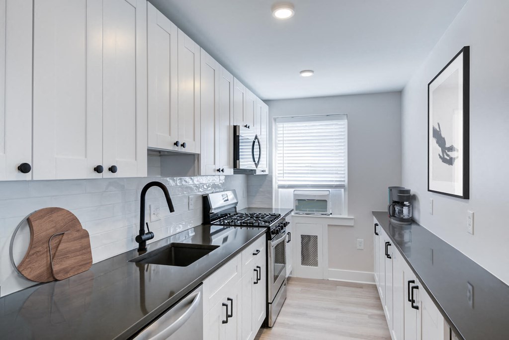 a white kitchen with black counter tops and a sink