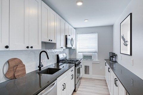 a white kitchen with black counter tops and a sink