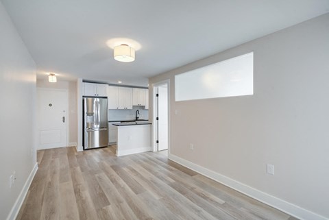 a renovated living room and kitchen with white walls and wood floors