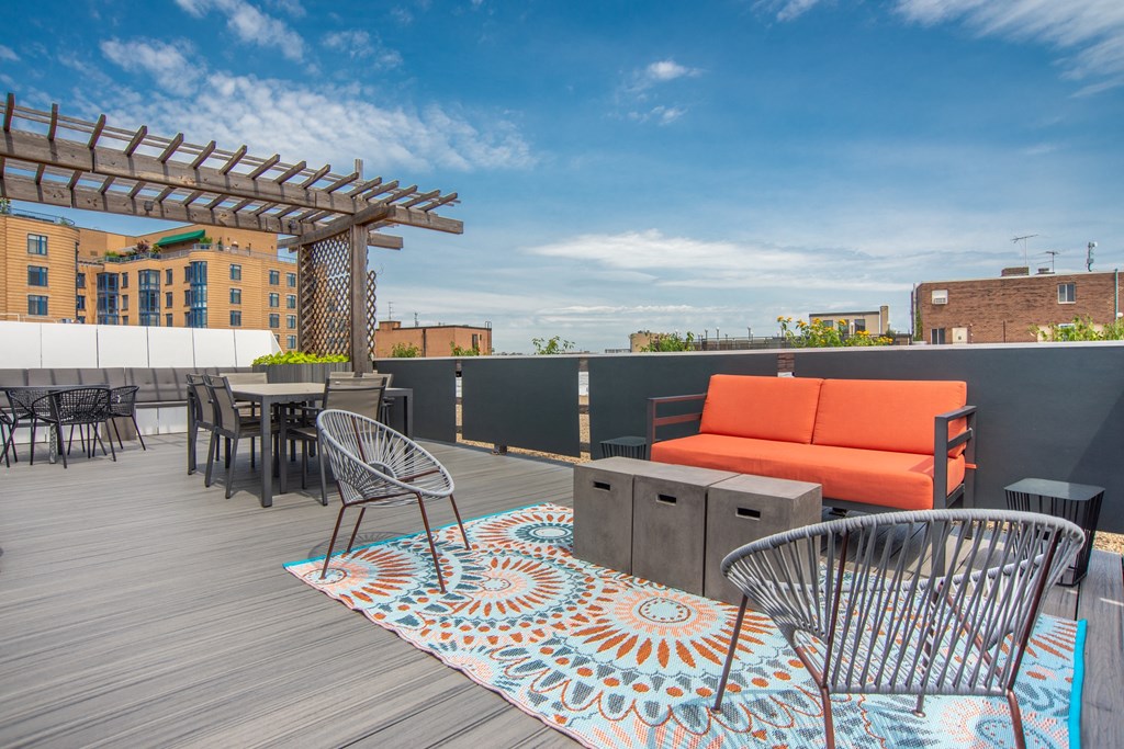 a rooftop patio with a couch and tables and a pergola