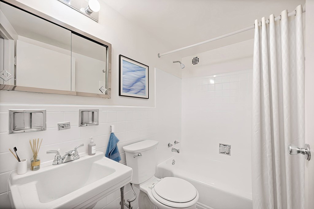 A white bathroom with a toilet, sink, and shower.