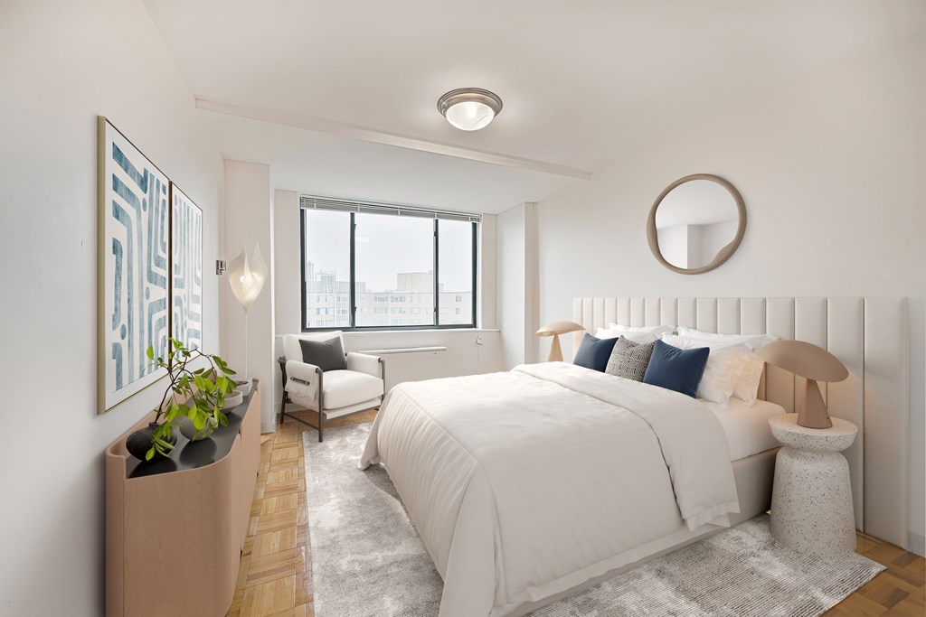 A bedroom with a large bed and a window overlooking the city.