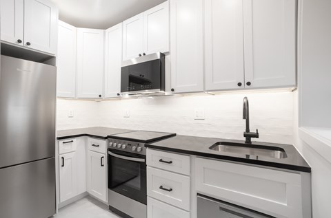 A modern kitchen with white cabinets and stainless steel appliances.