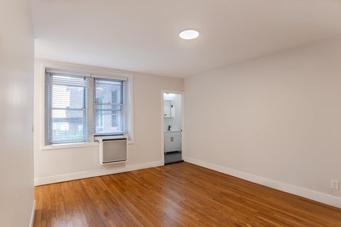 A room with a wooden floor and a window with blinds.