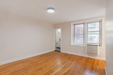A room with a wooden floor and a window with blinds.