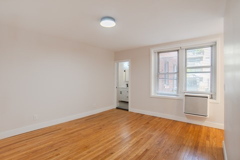 A room with a wooden floor and a window with blinds.