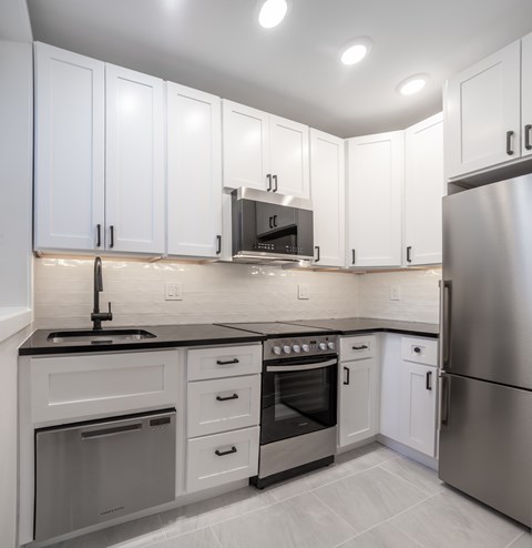 A modern kitchen with white cabinets and stainless steel appliances.