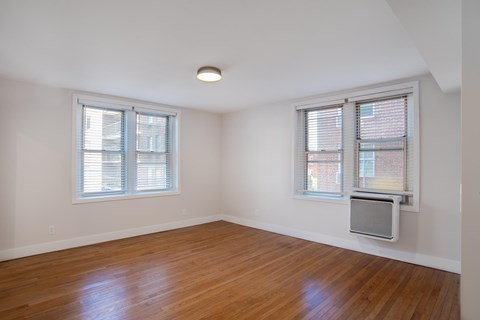 A room with wooden floors and two windows.