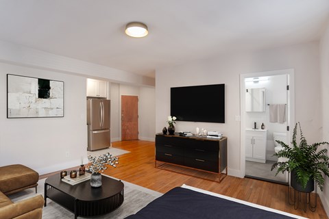 A living room with a brown chair, a black coffee table, a flat screen TV, and a potted plant.