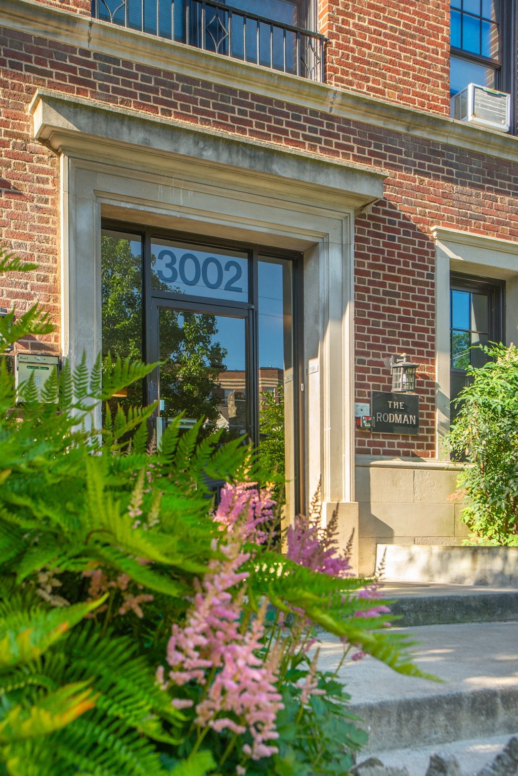 the front door of a brick building with flowers in front of it