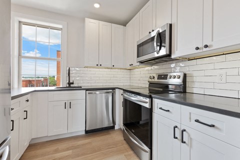 a white kitchen with stainless steel appliances and white cabinets