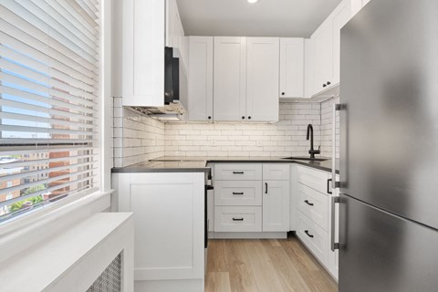 a kitchen with white cabinets and a stainless steel refrigerator