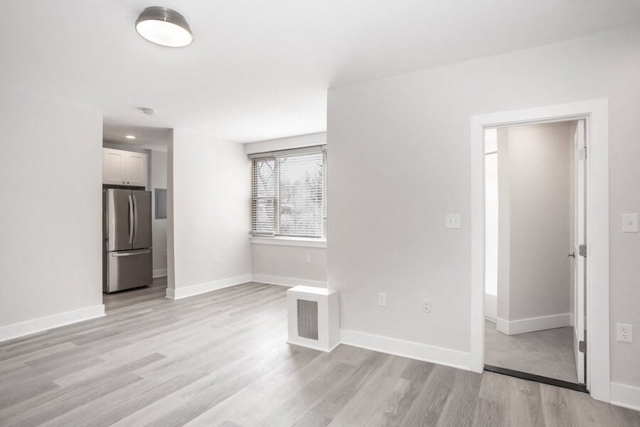 empty living room with a large window and a door to a kitchen