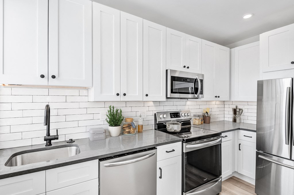 a white kitchen with stainless steel appliances and white cabinets