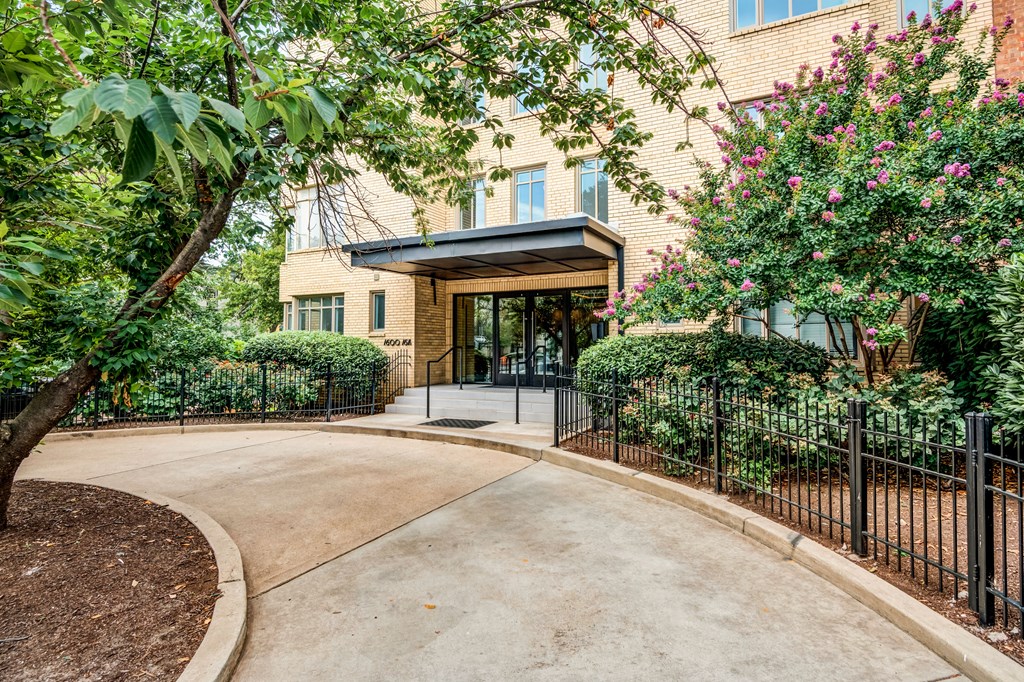 a walkway leading to a building with trees and a fence