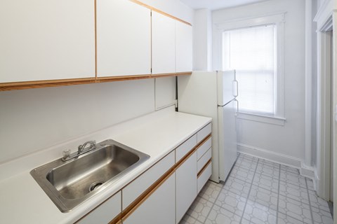 a kitchen with white cabinets and a sink and a refrigerator
