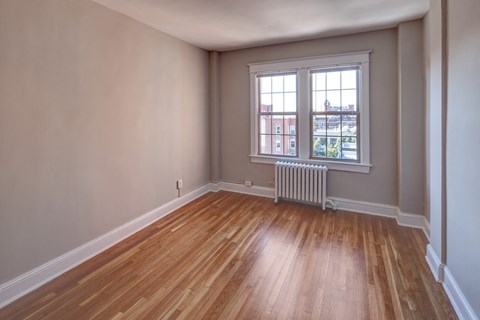 an empty living room with wooden floors and a window
