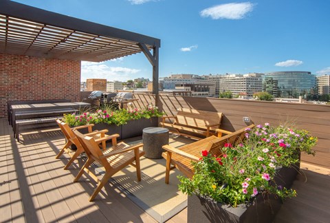 a roof terrace with wooden furniture and a city in the background